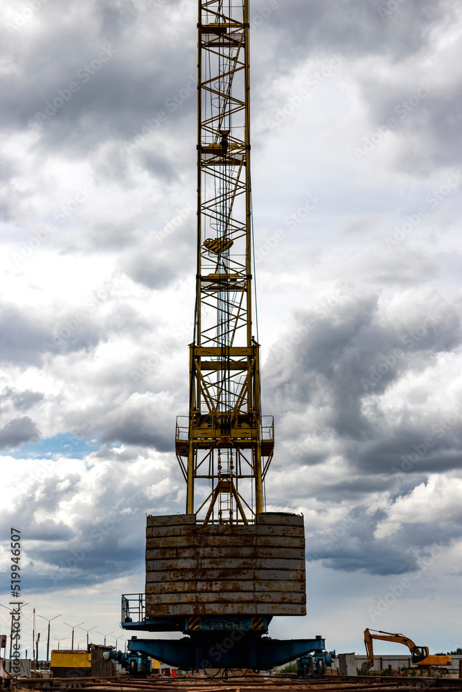 Tower crane close-up against the background of the cloudy sky. Modern building technologies.