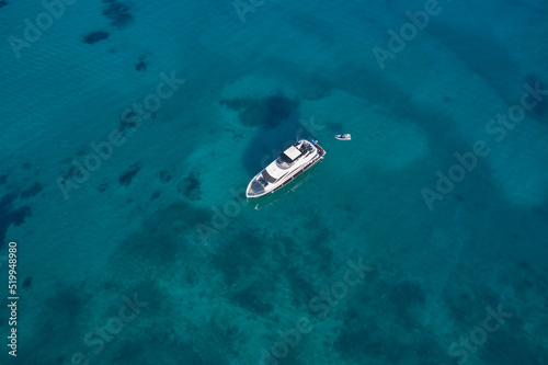 White boat on transparent water, top view. White yacht on transparent blue water top view. White yacht at anchor aerial view. © Berg