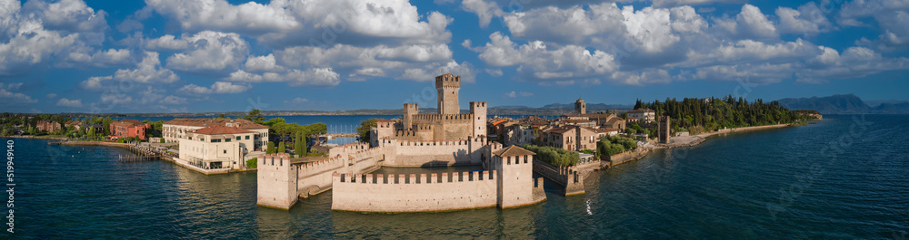 Panoramic aerial view of Scaligero Castle at sunrise. Historic part of the city of Sirmione view on Lake Garda, Italy. Panorama of the historic castle on the water on Lake Garda.
