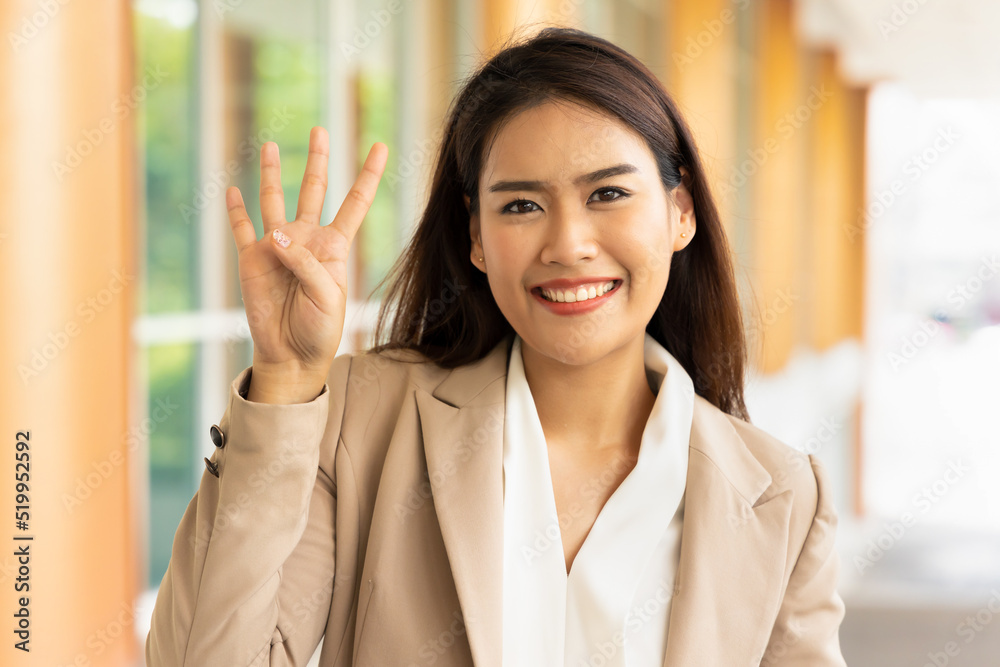 Happy smiling office worker woman pointing four fingers for number 4 or four points