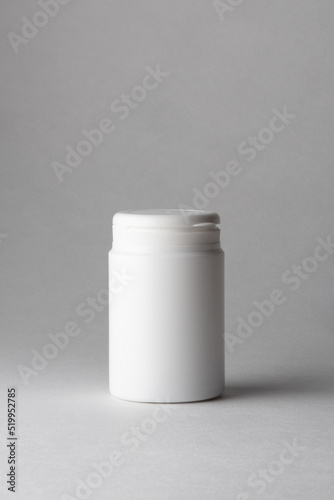 A white plastic pill container floating in the air on a gray background