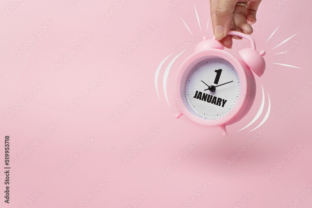 Obraz premium January 1st . Day 1 of month, Calendar date. The morning alarm clock jumping up from the bell with calendar date on a pink background. Winter month, day of the year concept.