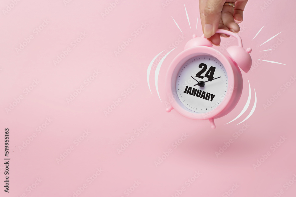 Obraz premium January 24th. Day 24 of month, Calendar date. The morning alarm clock jumping up from the bell with calendar date on a pink background. Winter month, day of the year concept.