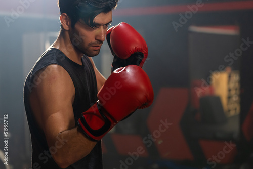 Caucasian active bodybuilder man athlete doing workout exercise in gym. Attractive handsome sportsman wear boxing gloves doing exercise by hitting a punching bag maintain muscle for health at fitness.
