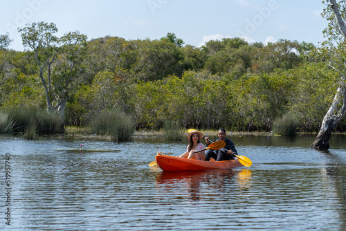 Asian attractive romantic young couple rowing kayak in a forest lake. Backpacker man and woman travel and kayaking on canoe in beautiful mangrove forest enjoy spend time on holiday vacation together. © Boonkung