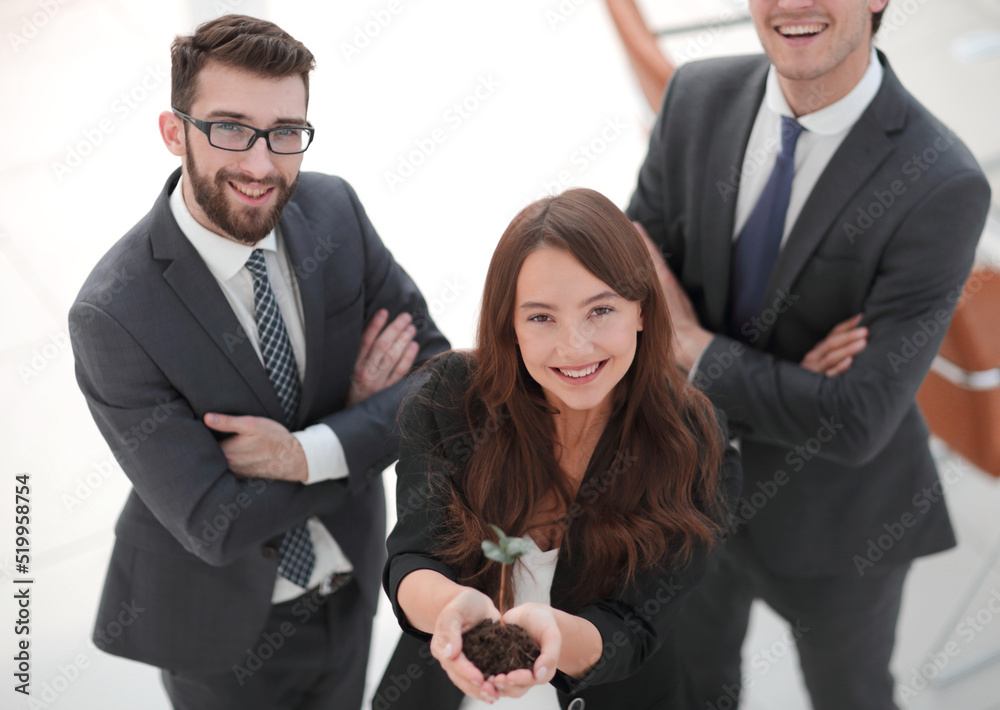 smiling business team shows a fresh sprout smiling business team shows a fresh sprout