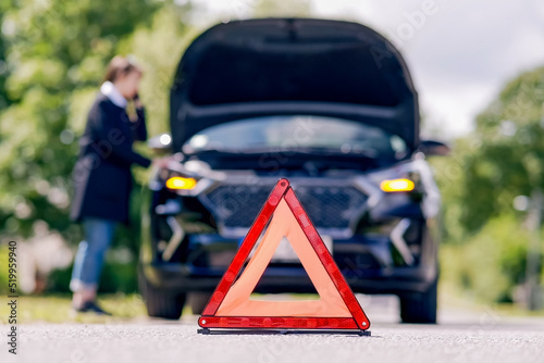 Red emergency stop sign and woman talking on the phone near a broken car on the road