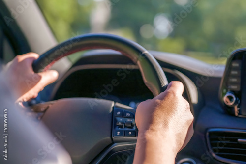 A man driving a car firmly holds on to the steering wheel with his hands. Driving a car on a weekend trip.
