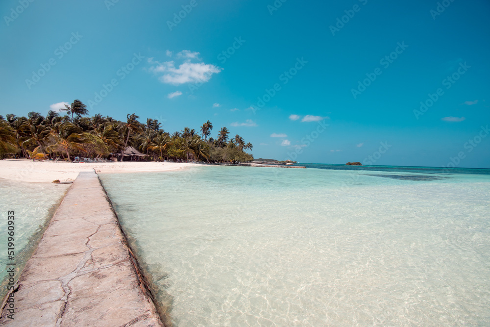 Pier leading onto tropical beach on an island in the Maldives in the summer Pier leading onto tropical beach on an island in the Maldives in the summer
