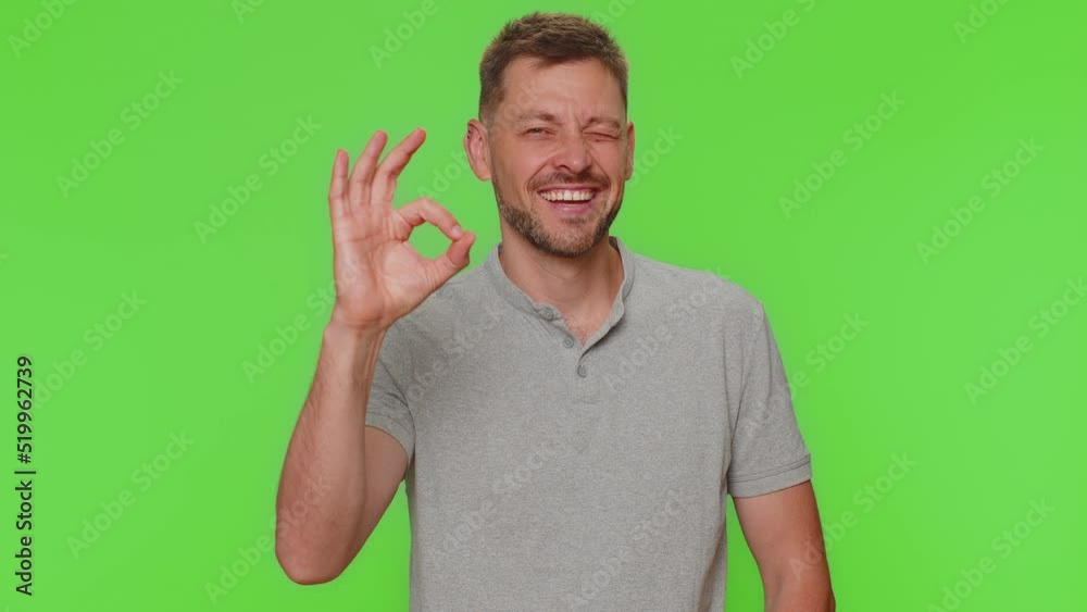 Ok. Bearded handsome young man looking approvingly at camera showing ok gesture, like sign positive, approve something good. Adult male guy isolated alone on green chroma key studio background indoors Ok. Bearded handsome young man looking approvingly at camera showing ok gesture, like sign positive, approve something good. Adult male guy isolated alone on green chroma key studio background indoors