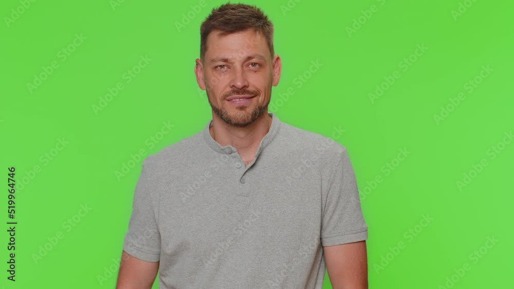 Smiling playful happy man blinking eye, looking at camera with toothy smile, winking and flirting, expressing optimism. Adult male guy isolated alone on green chroma key studio background indoors Smiling playful happy man blinking eye, looking at camera with toothy smile, winking and flirting, expressing optimism. Adult male guy isolated alone on green chroma key studio background indoors