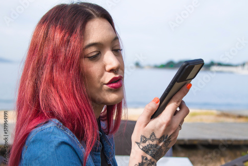 beautiful smiling redhead girl with phone in seascape
