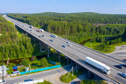 Active traffic of cars on a wide highway and a bridge. Flight over the automobile bridge across the river Lattice. Yekaterinburg. Russia