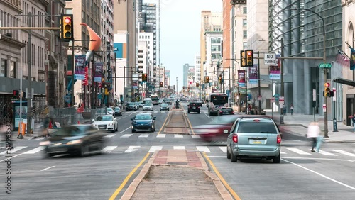 Downtown cityscape time-lapse of car traffic transportation, people walk cross road at junction intersection in Philadelphia, USA. Public transport, American city life, or commuter lifestyle concept