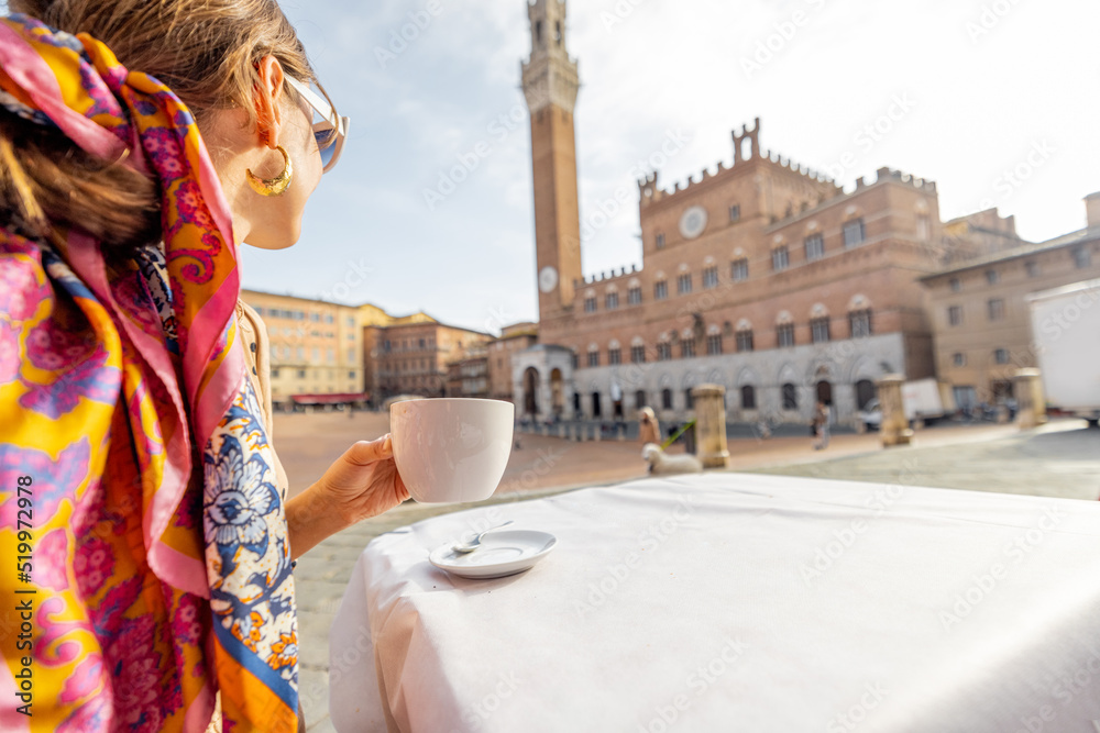 Woman having italian breakfast with coffee and croissant, sitting at outdoor cafe with beautiful view on main square of Siena city. Concept of italian lifestyle and travel old towns in Tuscany