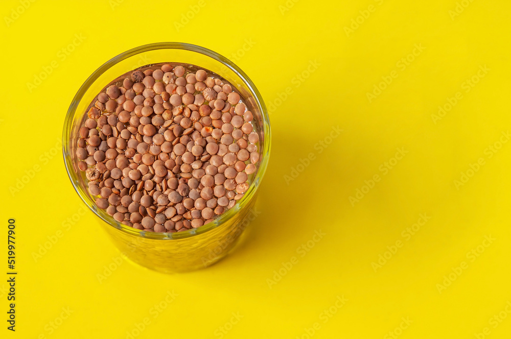 a glass with lentils on a yellow background a glass with lentils on a yellow background