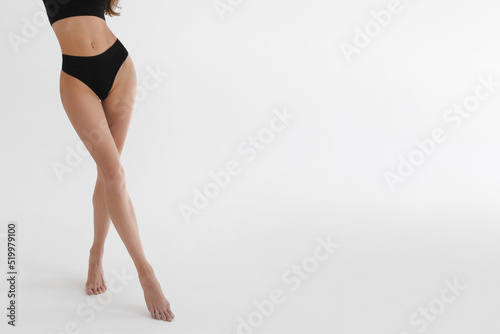 Tanned slim legs of a woman on white studio background. Close up of fitness model in sports clothing. Underpants or underwear advertising. Skin care or diet banner © mlphoto