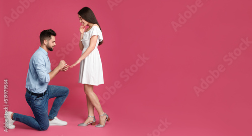 Man with engagement ring making marriage proposal to girlfriend on pink background, space for text. Banner design
