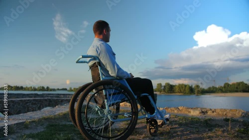 young man in a wheelchair smiling and looking out into the distance.An incapacitated guy on the backdrop of the beach and clouds thinking about life