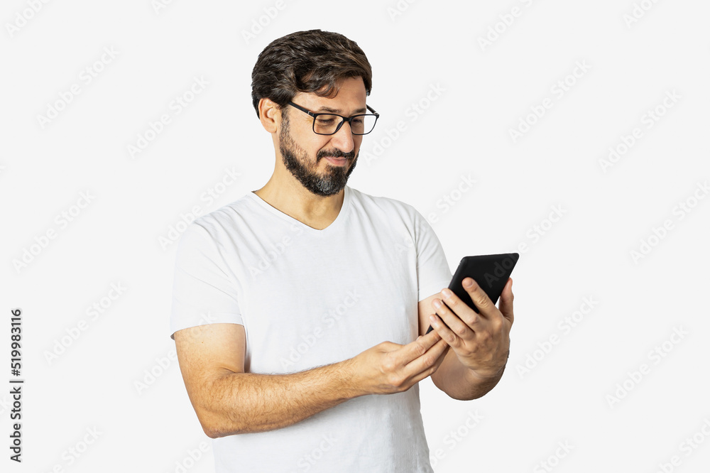Portrait of a young man, cheerful, wearing a T-shirt, standing, isolated on a white background, using a cell phone. Portrait of a young man, cheerful, wearing a T-shirt, standing, isolated on a white background, using a cell phone.