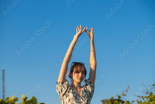 beautiful girl against the sky. arms raised lightly above the head against the sky. feminine gentle hands. photo for advertising cosmetic services. A beautiful fashion model girl enjoys nature, b