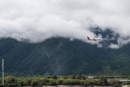 Airplane flying through the clouds over the pine forest covered mountains