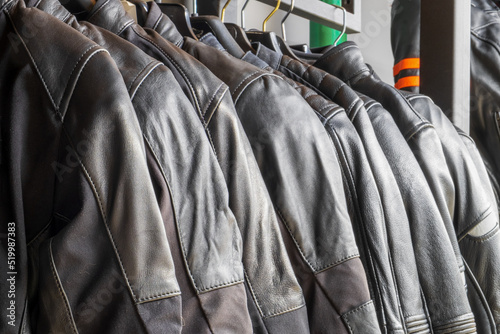 Black leather jackets for motorcyclists hang in a row close-up