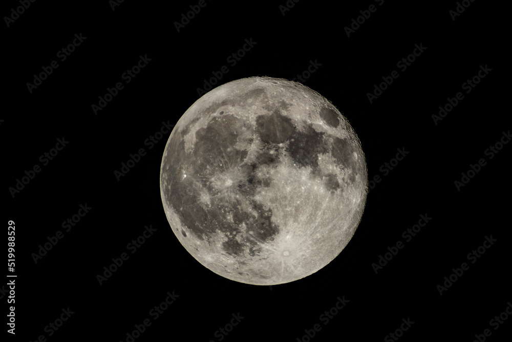 Details of the full moon photographed by a telescope, craters and mountains are visible far away.