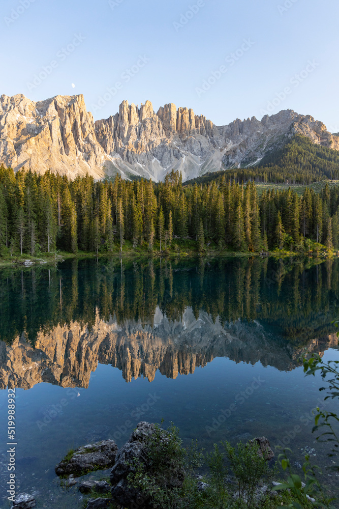 Splendid view of Lake Carezza in South Tyrol. The mountains and the forest are perfectly reflected on the lake, a suggestive image. A dream place for a relaxing holiday in nature.