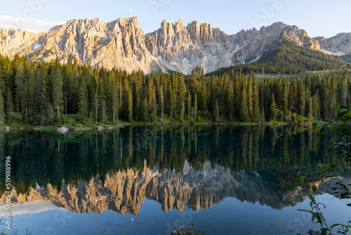 Splendid view of Lake Carezza in South Tyrol. The mountains and the forest are perfectly reflected on the lake  a suggestive image. A dream place for a relaxing holiday in nature.