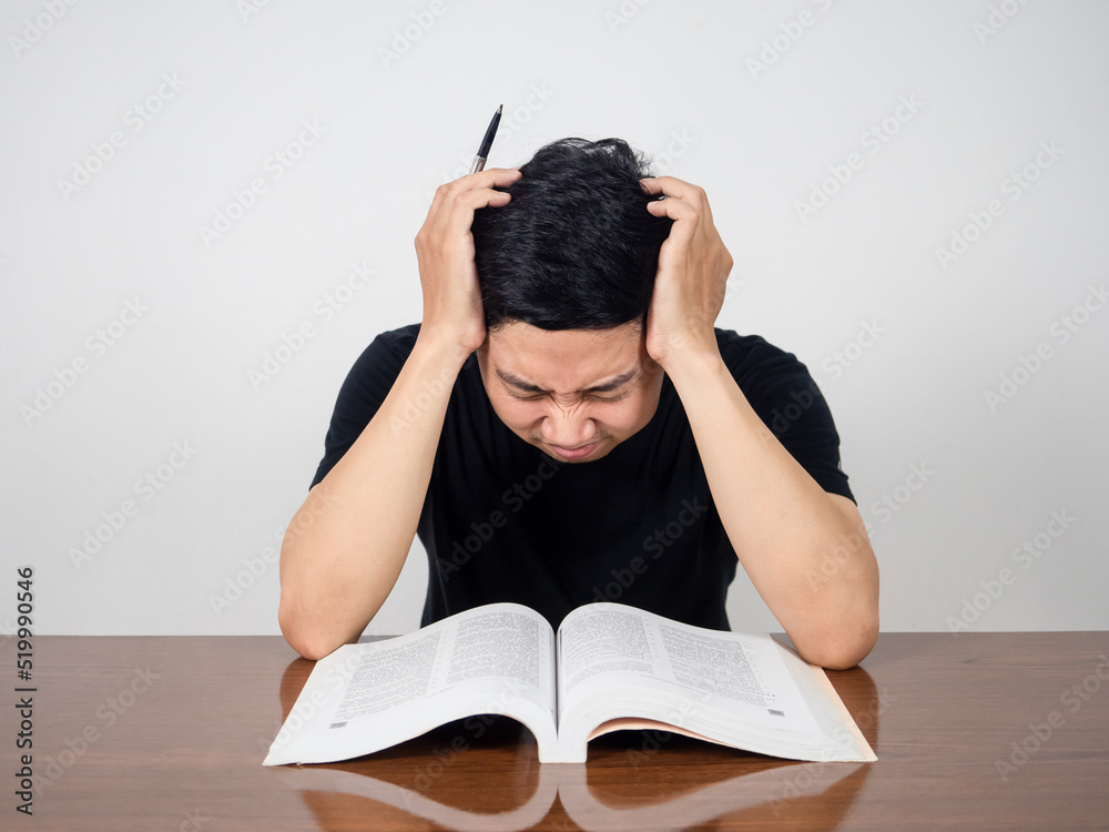 Asian man feels headache with reading book on the table Asian man feels headache with reading book on the table
