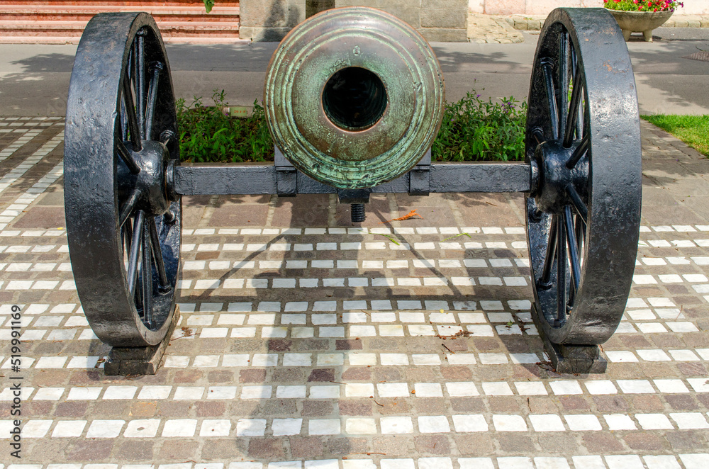 An old cannon on a gun carriage exposed on the street An old cannon on a gun carriage exposed on the street