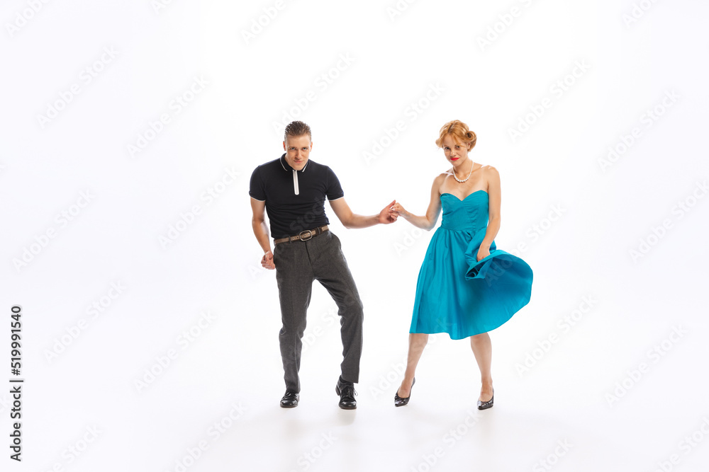 Naklejka premium Portrait of stylish young couple, man and woman dancing isolated over white studio background. Retro disco party