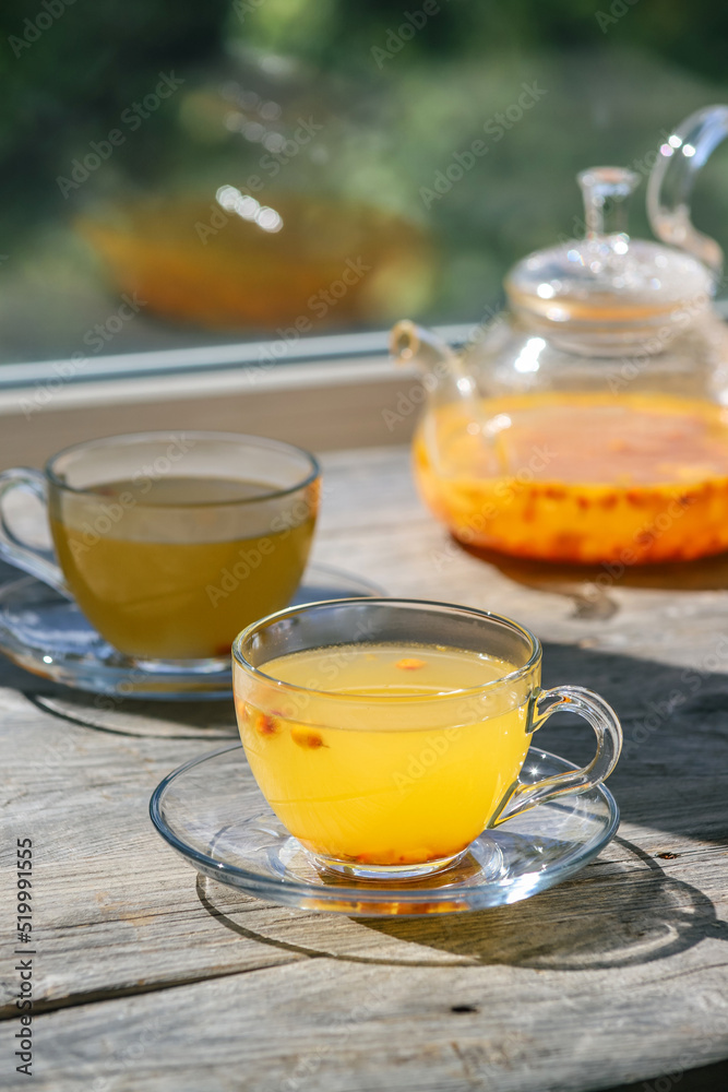 Sea buckthorn tea in glass cups and teapot on a wooden windowsill. Healthy vitamin drink Sea buckthorn tea in glass cups and teapot on a wooden windowsill. Healthy vitamin drink
