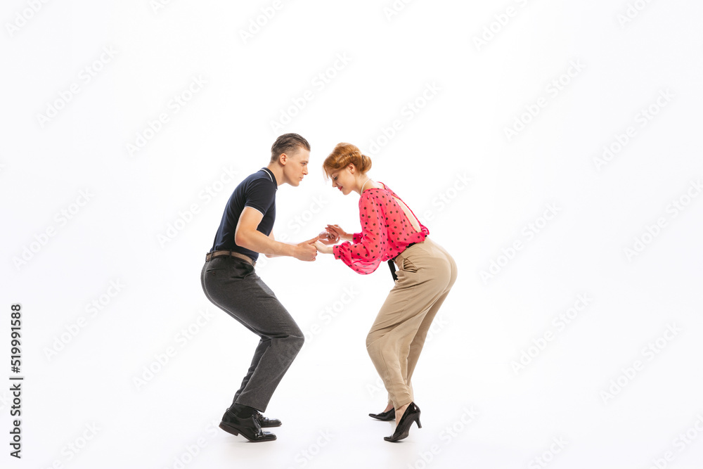 Portrait of stylish young couple, man and woman dancing boogie woogie isolated over white studio background Portrait of stylish young couple, man and woman dancing boogie woogie isolated over white studio background