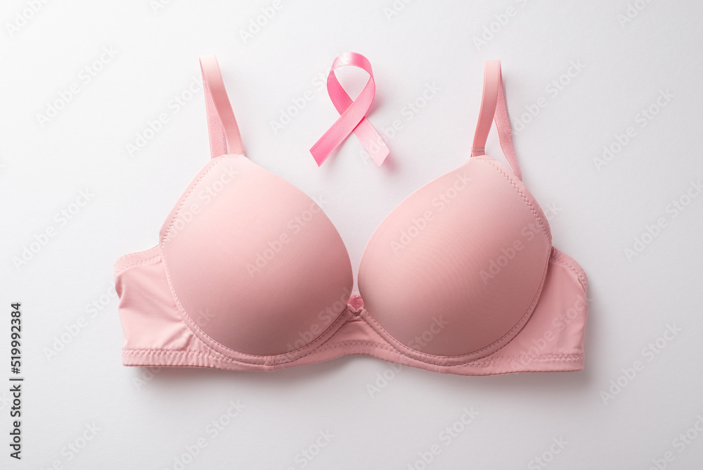 Breast cancer awareness concept. Top view photo of pink brassiere and pink ribbon on isolated white background Breast cancer awareness concept. Top view photo of pink brassiere and pink ribbon on isolated white background