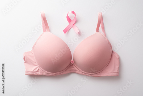 Breast cancer awareness concept. Top view photo of pink brassiere and pink ribbon on isolated white background