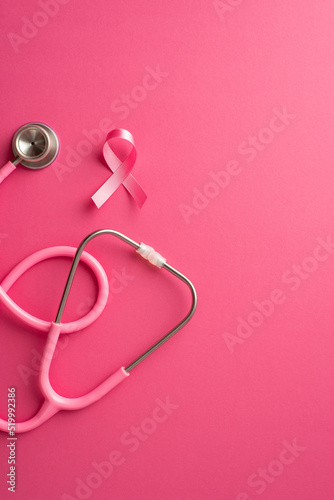 Breast cancer awareness concept. Top view vertical photo of pink silk ribbon and stethoscope on isolated pink background