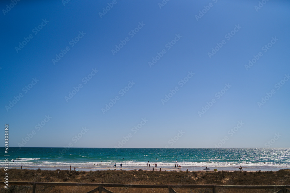 vista de playa abarrotada con el mar en calma de fondo