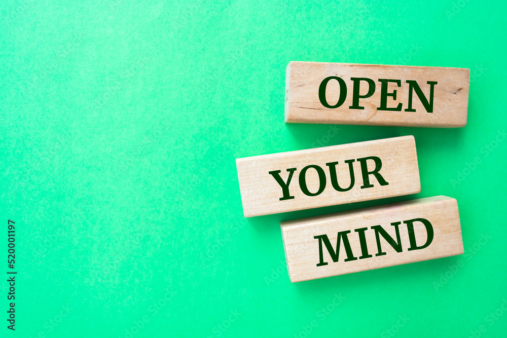 Open Your Mind words on wooden blocks on green background.