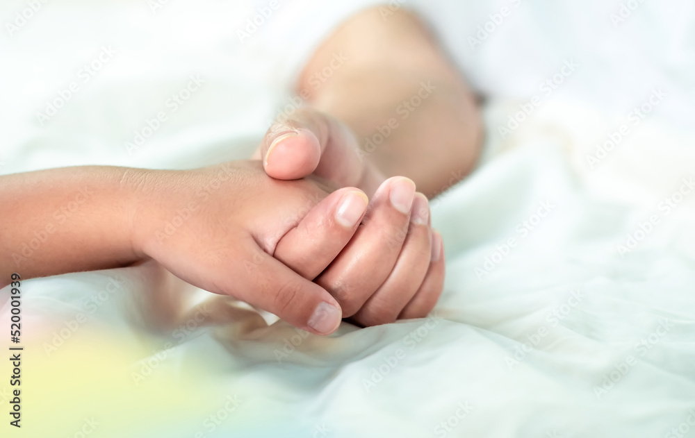 Close up mother holding baby's hand on white bed, love bonding, encouragement and warmth take care of each other in the family, Family concept Close up mother holding baby's hand on white bed, love bonding, encouragement and warmth take care of each other in the family, Family concept