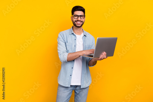 Photo of confident handsome hispanic man enjoy working from home dressed trendy jeans outfit spectacles isolated on yellow color background