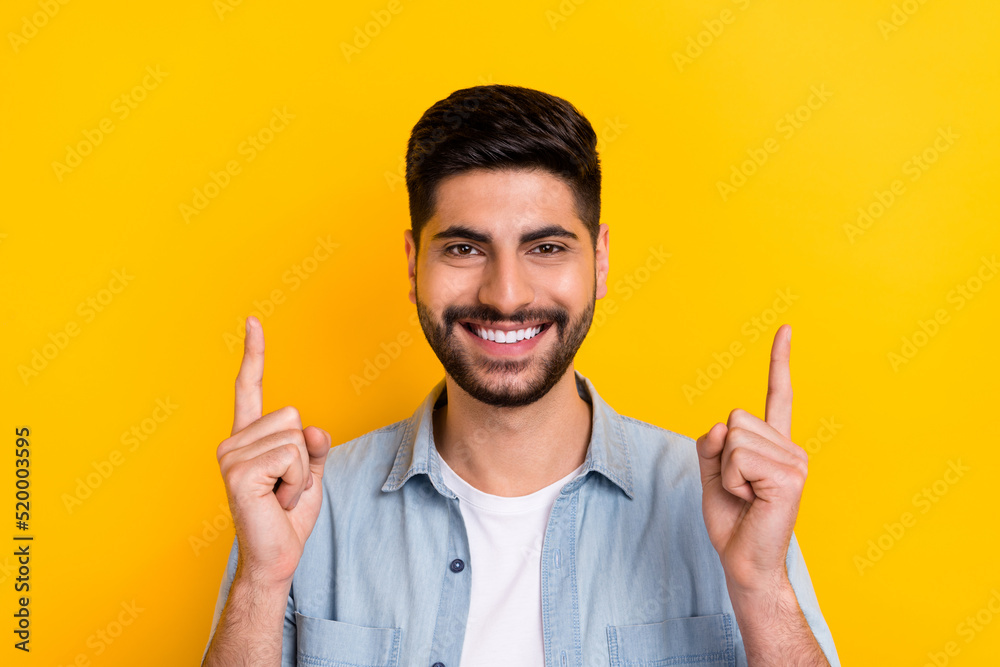 Portrait of young stylish man showing fingers up directing empty space showing good weather isolated on yellow color background Portrait of young stylish man showing fingers up directing empty space showing good weather isolated on yellow color background