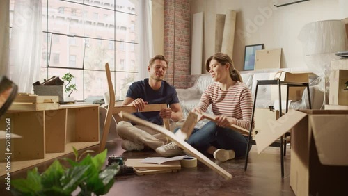 Family Moving in and Home Renovations: Happy Couple Assembles Furniture as a Team, Girlfriend Reads Instructions and Boyfriend Follows them with some Force. New Apartment for Young Partners in Love