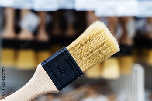 Paint brush with a wooden handle on the background of a showcase. Selection and purchase of tools for interior and exterior decoration. Foreground