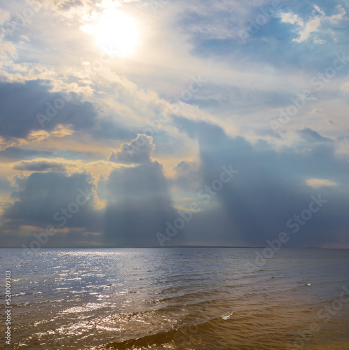 sun push through the dense clouds over a sea bay