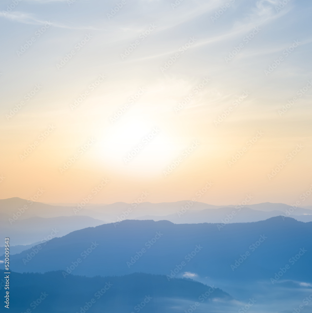 mountain ridge silhouette in blue mist at the sunrise