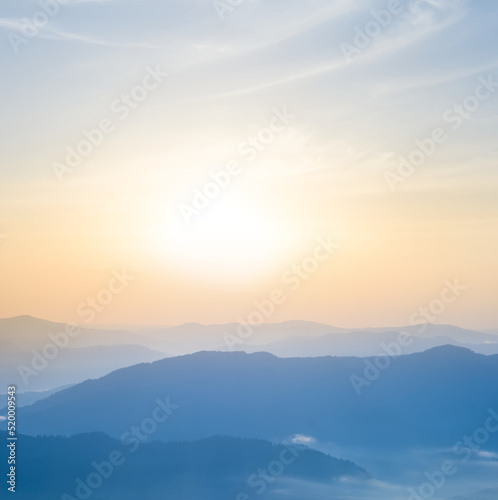 mountain ridge silhouette in blue mist at the sunrise