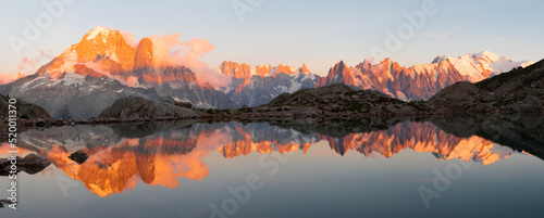 The panorama of Mont Blanc massif Les Aiguilles towers, Grand Jorasses and Aiguille du Verte over the Lac Blanc lake in the sunset light.