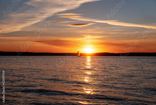 Peaceful sunset on the sea. Sailing yacht on the background of the setting sun. Focus on the foreground